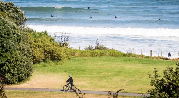 cyclist and surfers along the coastline near Fitzroy Beach